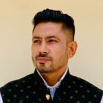 Indian groom in traditional attire posing against a wall in Jaipur.